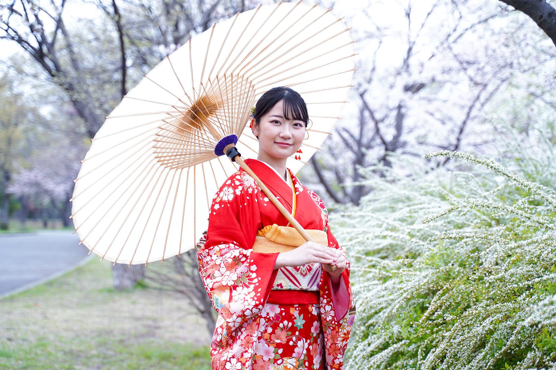 赤い振袖で和傘を持つ成人式の屋外ポートレート